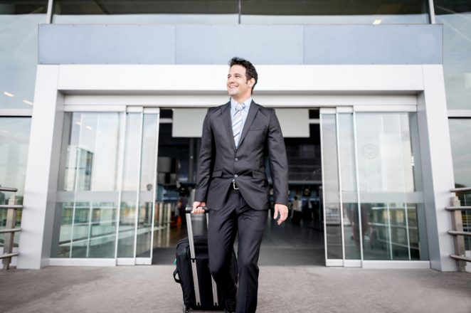 A male banker walking outside and away from a building